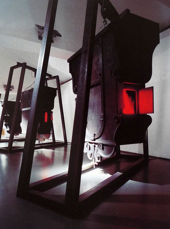 Barokk katodikus mozgások (Movimenti catodici barocchi), fa gyóntatószék, 2 monitor, elektromos motor, fémállvány © Archivio PlessiBaroque cathodic movements (Movimenti catodici barocchi), wooden confessional, 2 screens, electric motor, metal bearer © Archivio Plessi Movimenti catodici barocchi