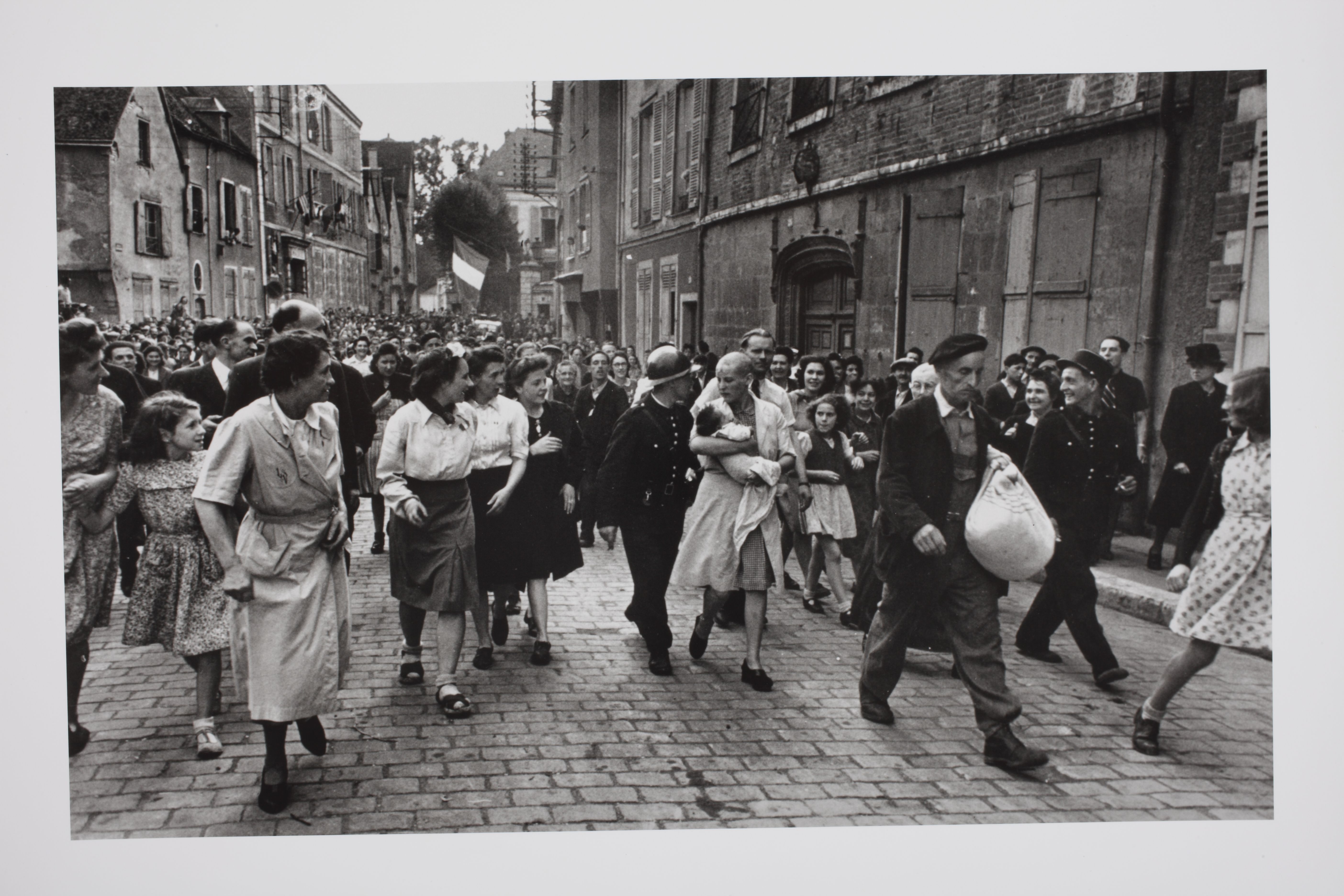 Chartres, August 18, 1944. Just after the Allies had liberated the town, a Frenchwoman who had had a baby by a German soldier was punished by having her head shaved. Here she is seen being marched home. Her mother (barely visible over the right shoulder of the man at right carrying cloth sack) was similarly punished. Fényképezte Robert Capa © International Center of Photography, New York. A  Magyar Nemzeti Múzeum gyűjteménye Chartres
