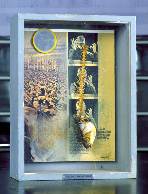 Wolf Vostell, Zyklus Mania, Völkermord, / Mária ciklus - Népírtás 1973 mirror, fish skeleton, pencil, and bluring on magazine with nail in box with sign, / tükör, halcsontváz, ceruza, elmosódott újságlap, feliratos doboz szöggel  40.5 × 30.2 × 11.7 cm Private collection ©The Wolf Vostell Estate/VG Bild Kunst. Courtesy Archivo Happening Vostell, Junta de Extremadura